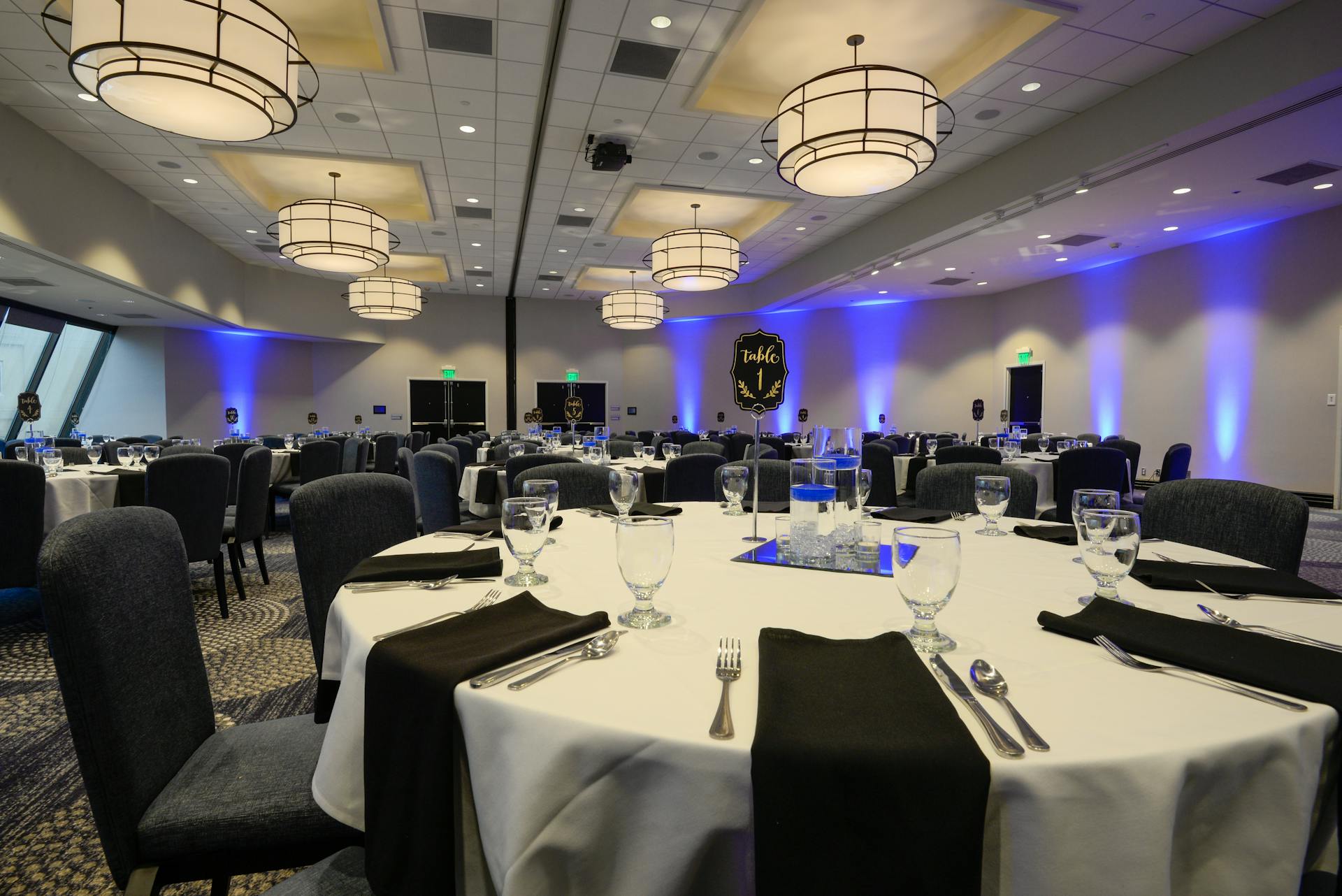 A modern black-and-white themed function venue with elegant tables, chairs, and flush mount lights, ideal for stylish events.
