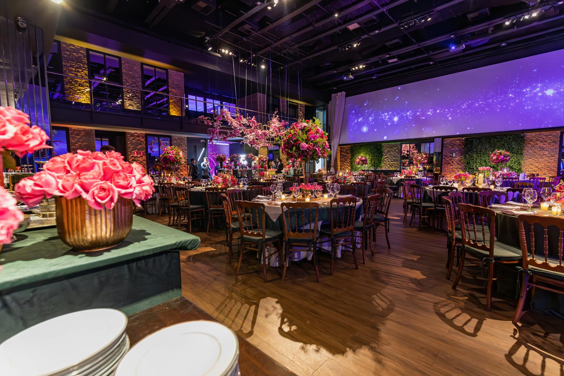 A charming function venue with tables, chairs, and pink floral decorations, perfect for celebrations.