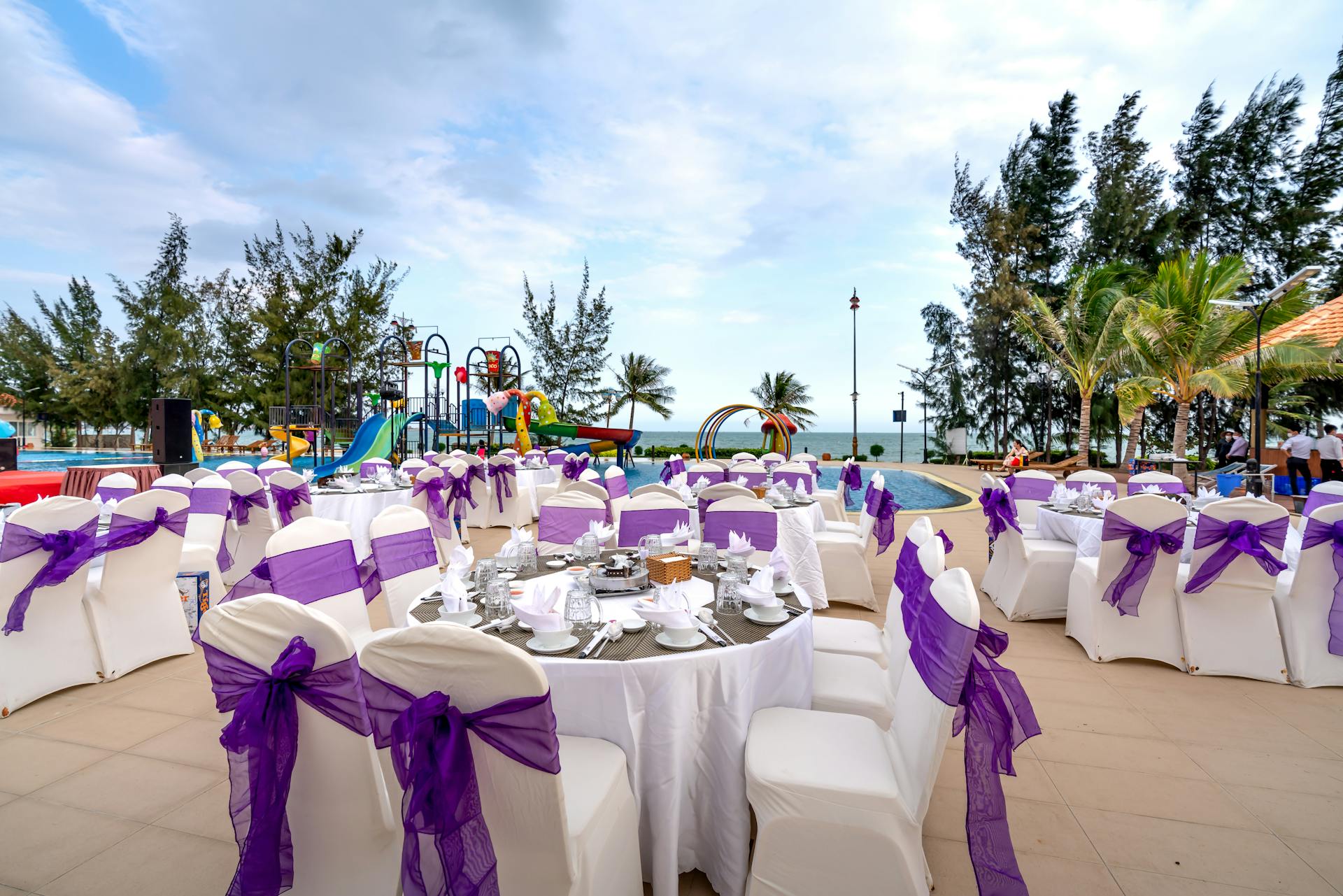 Elegant outdoor function venue with tables and chairs decorated with purple bows, ideal for weddings and celebrations.